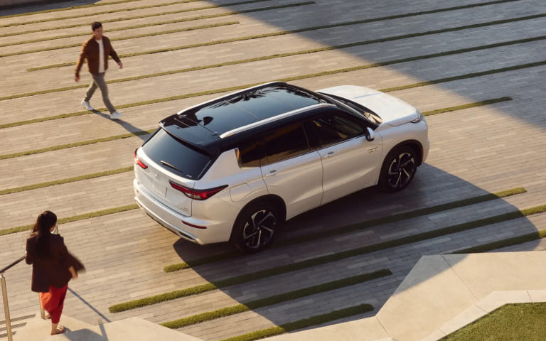 Customer walking near a Mitsubishi SUV while exploring lease-end options